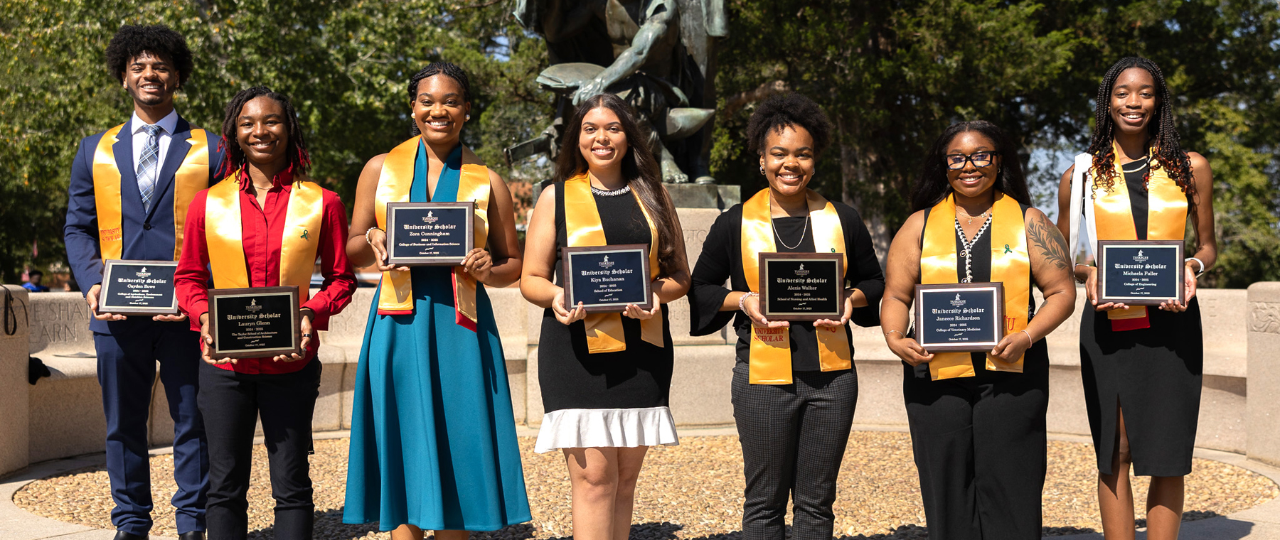 Honor students at monument holding certificates