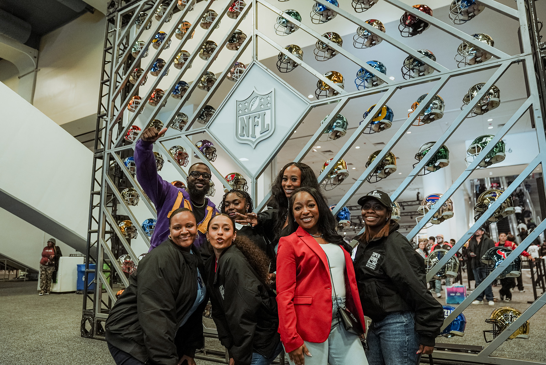 Students pose in front of helmet wall at the Super Bowl