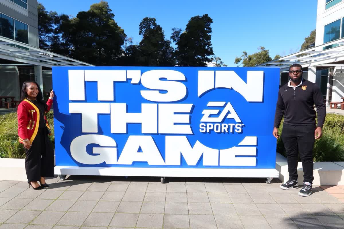 Chelsea and Terrance pose near a sign at the Super Bowl