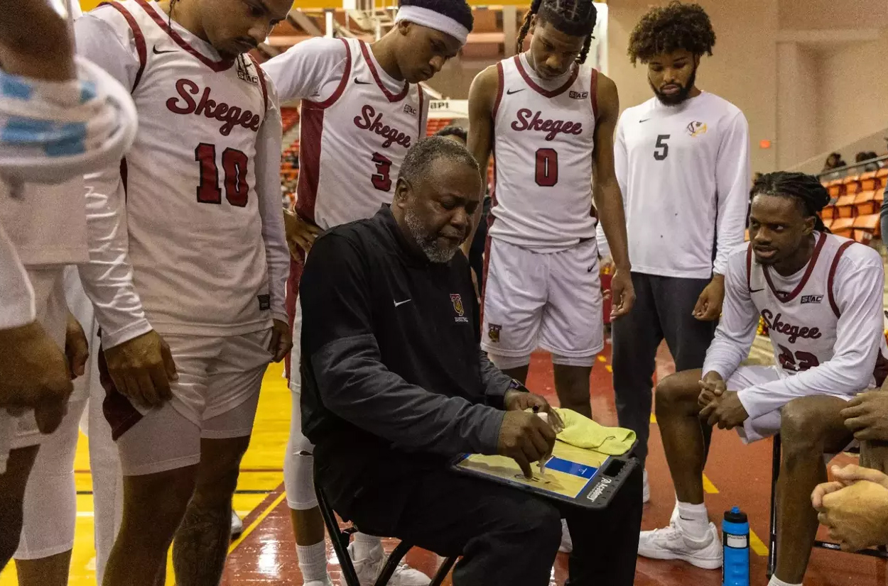 Coach goes over play with men basketball players