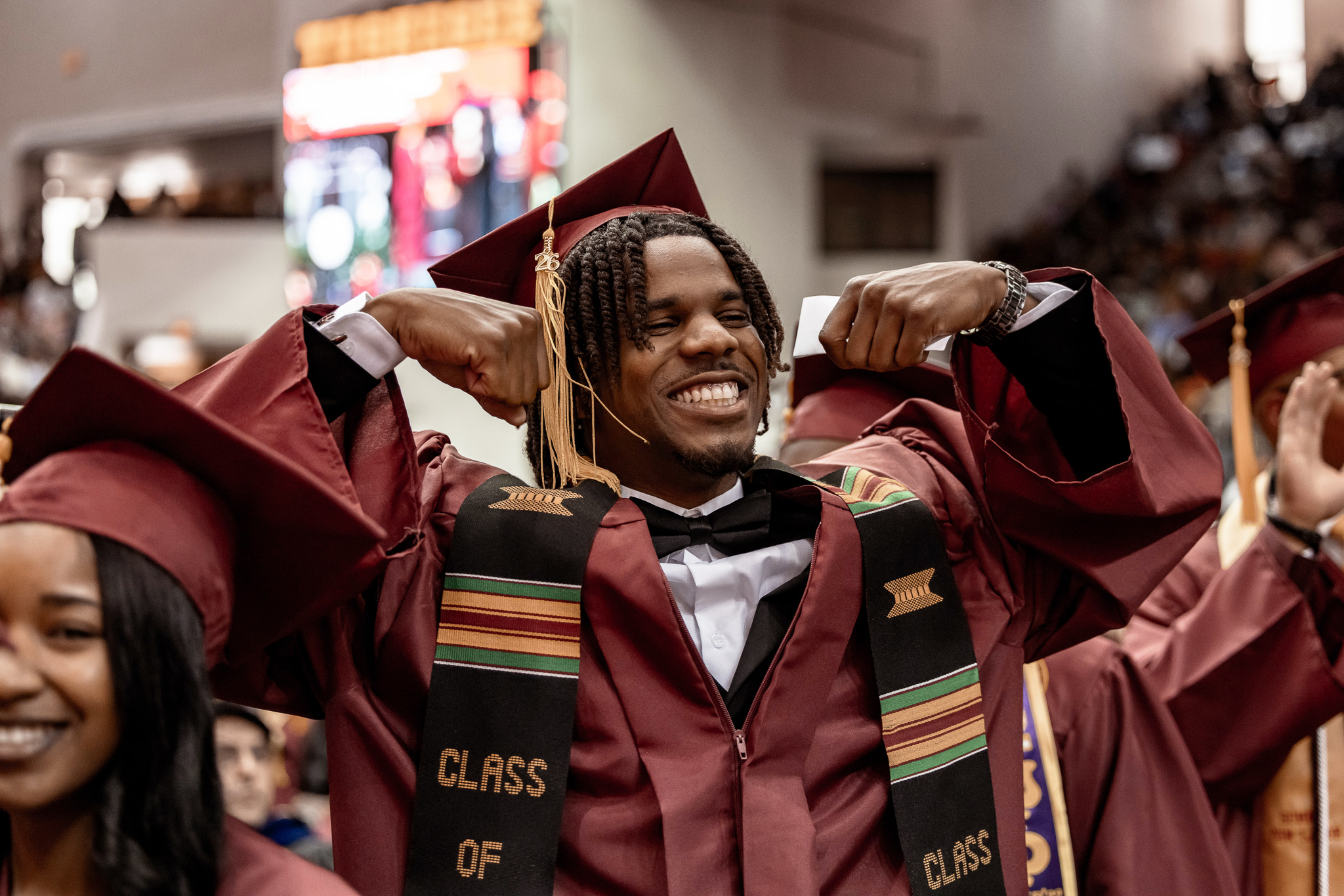 A male student graduate flexing his muscles at Commencement