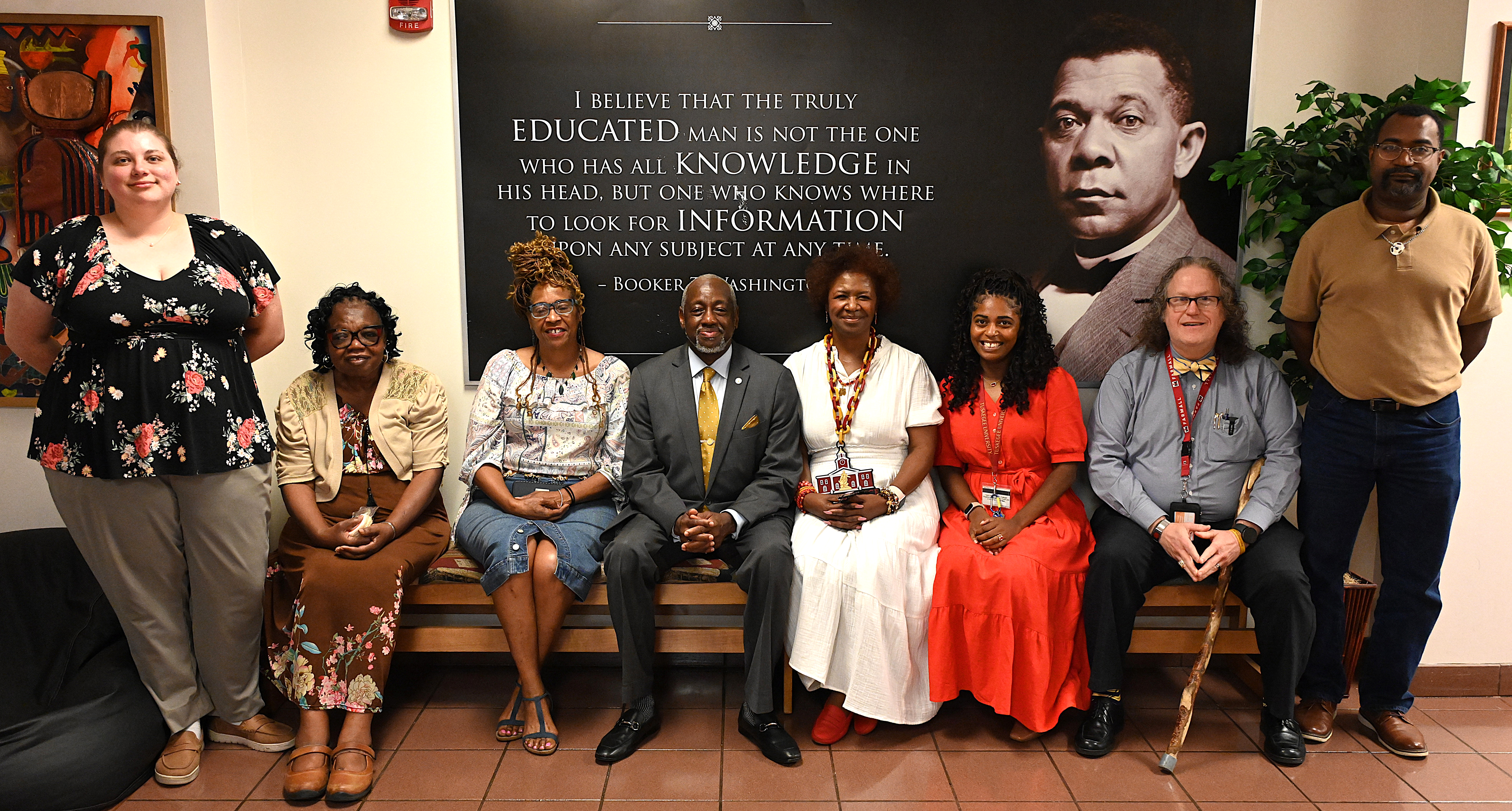 Dr. and Mrs. Brown with Library staff in front of a Booker T. Washington quote