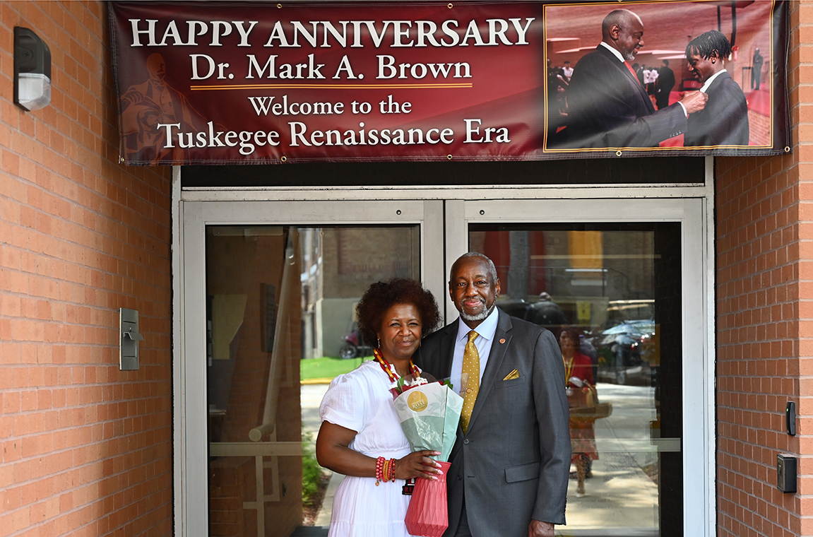 Dr. and Mrs. Mark Brown standing in front of Anniversary sign at Kresge Center entrance