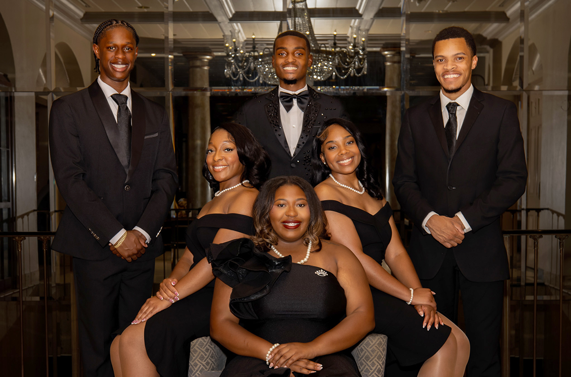 Tuskegee University Royal Court dressed in black pose for a group picture in the lobby.