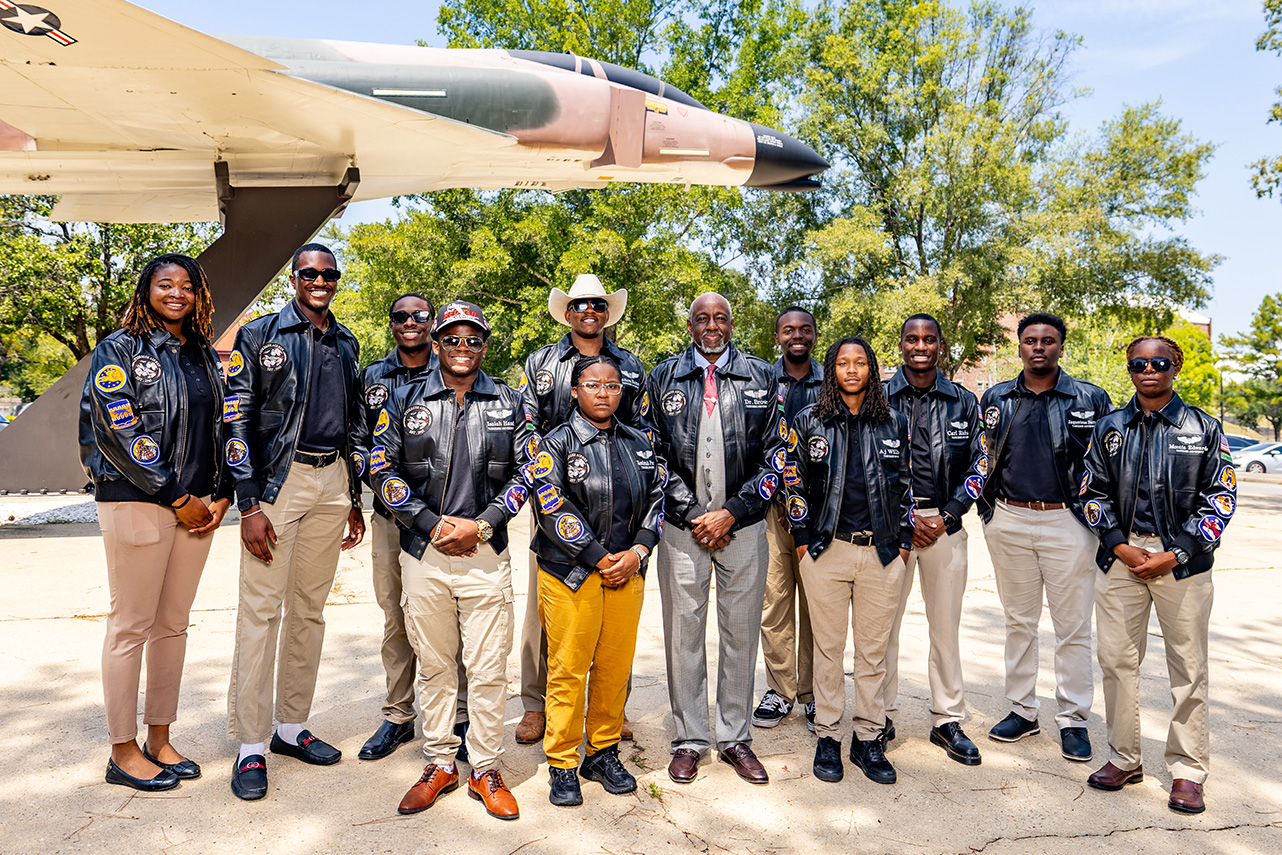 Dr. Brown and student aviators stand under the Gen. Daniel Chappie James airplane