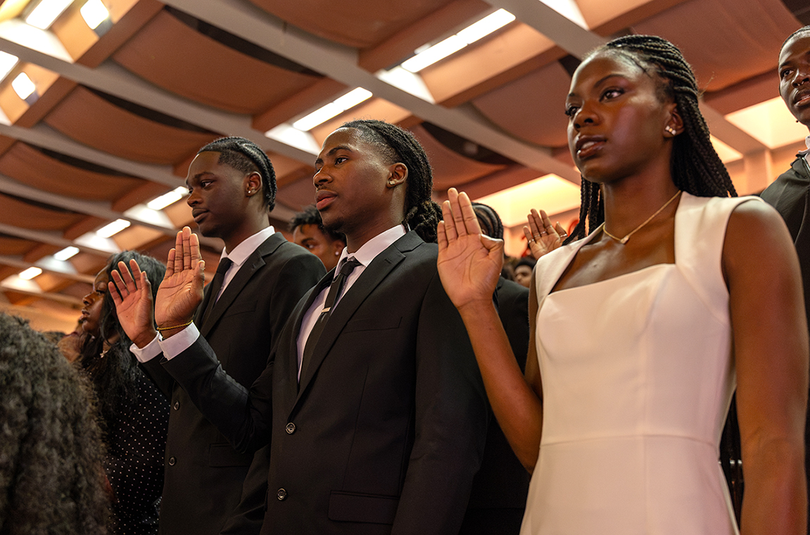New students with hands raised take the pledge