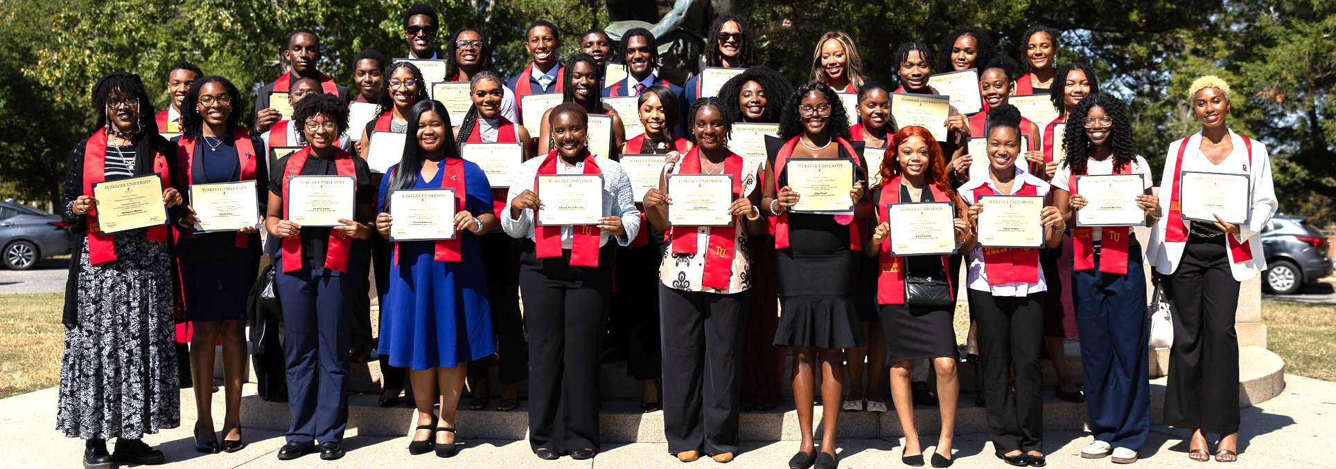 Student Scholars holding certificates at the monument