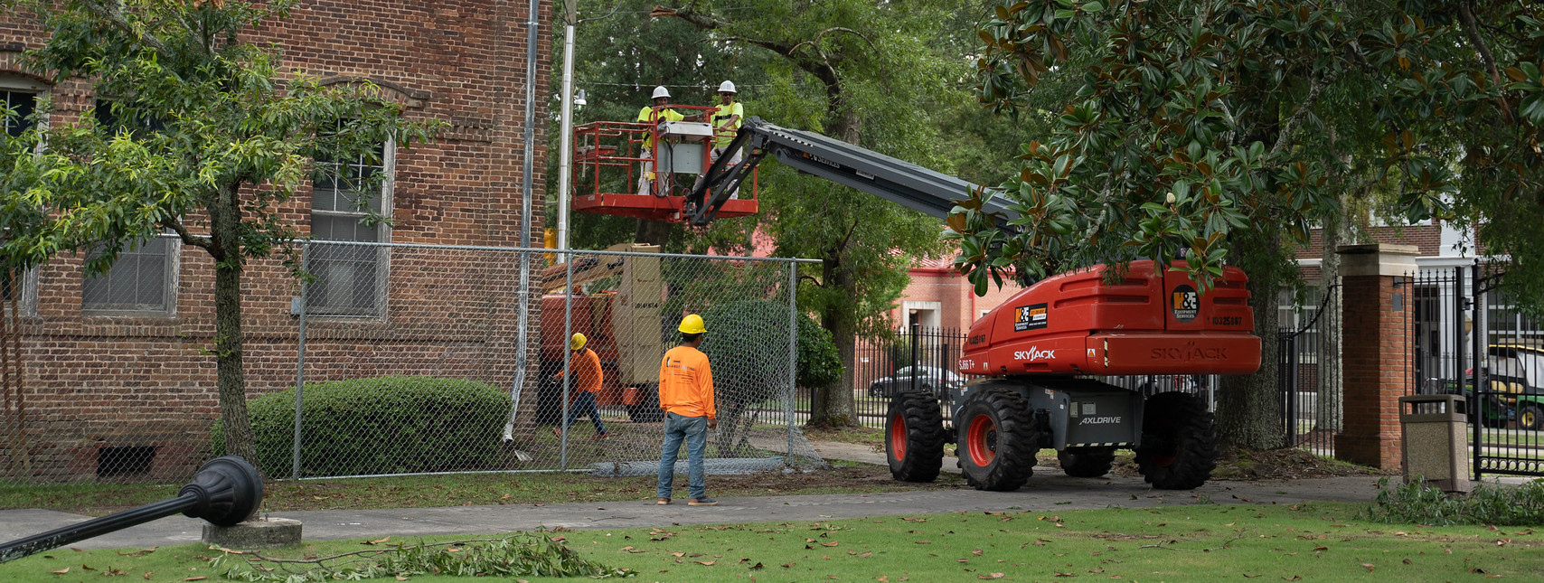 Maintenance workers with machine to cut tree branches