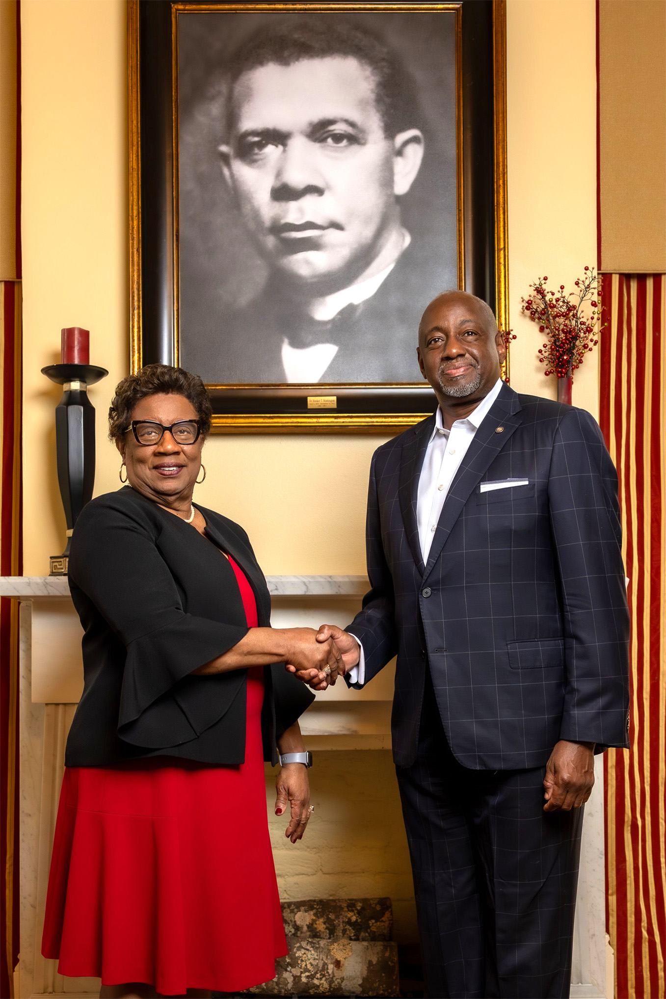 Dr. Charlotte P. Morris and Dr. Mark Brown shake hands in front of picture of Booker T. Washington.