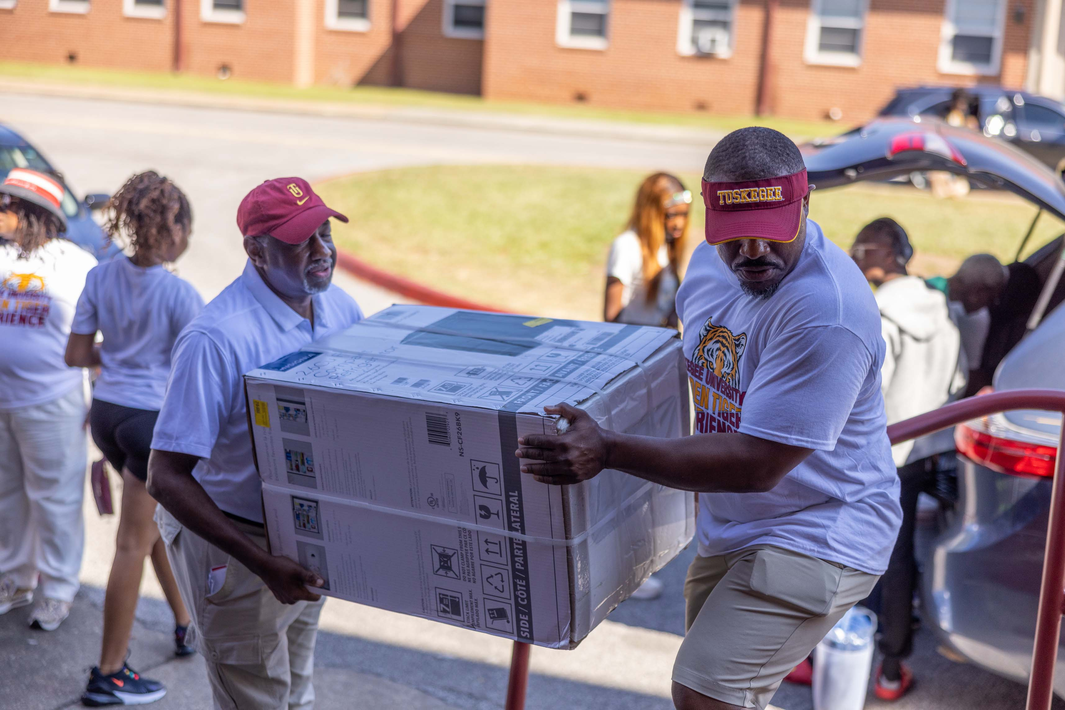 President Brown and Trustee Porter carry item into dorm.