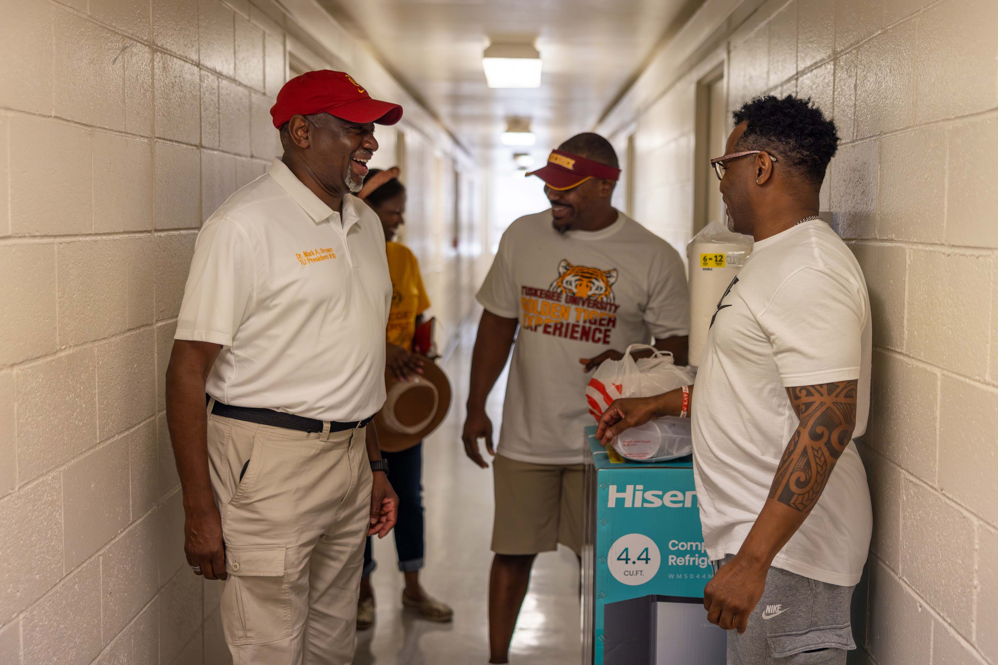 President Brown talks with parent in dorm hallway.