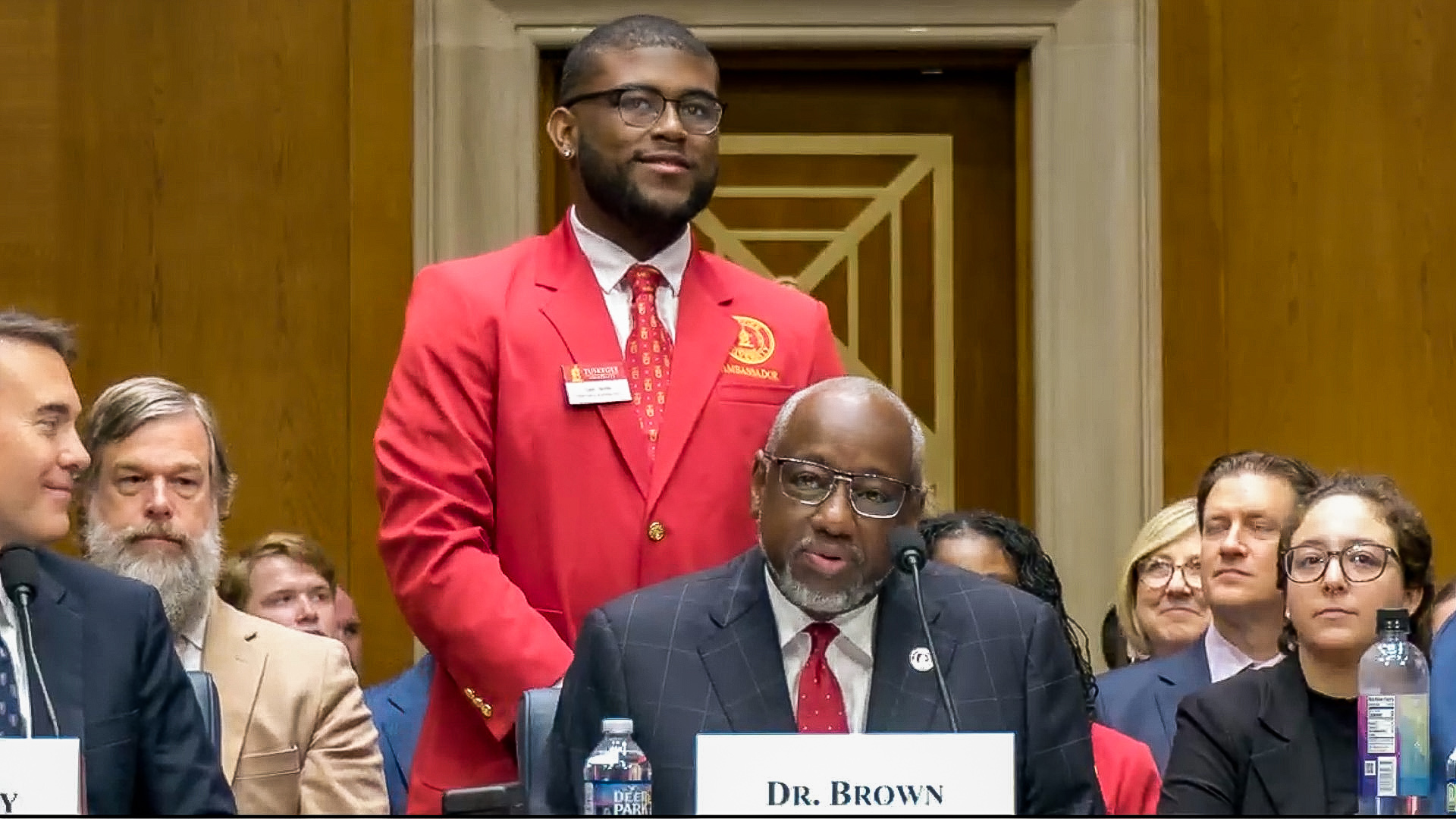 Tyler Smith stands as Dr. Brown introduces him during Senate hearing.