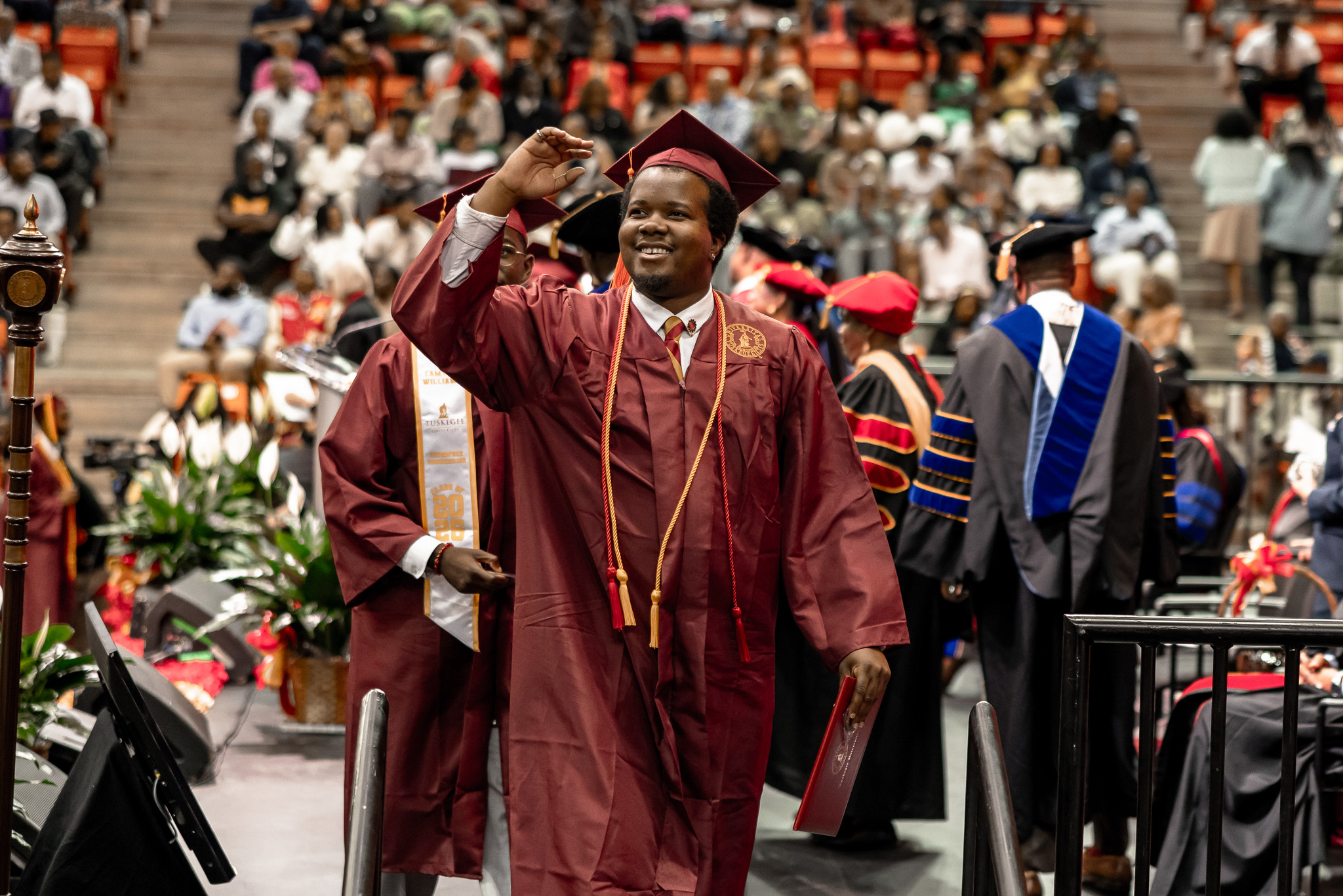 Male graduate walks down isle at Commencement ceremony