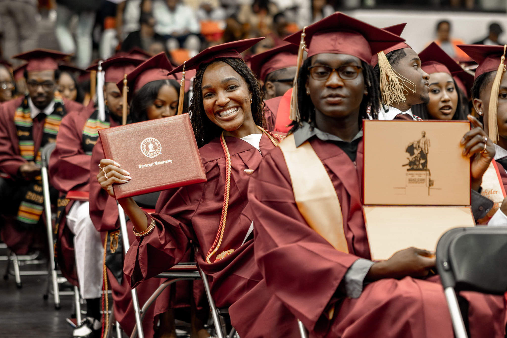 Female and male graduates hold up their diplomas