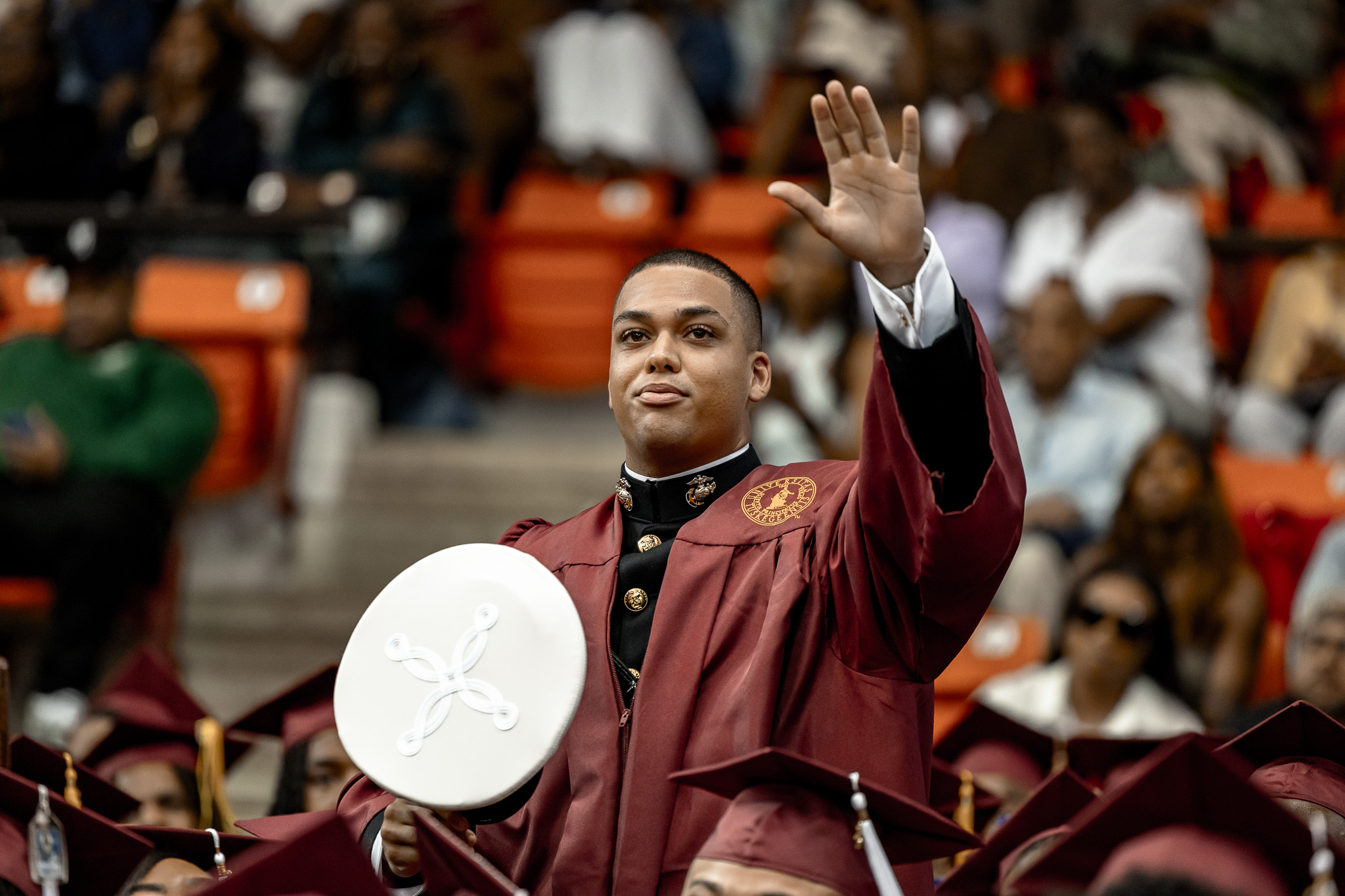 A male graduate who is a newly commissioned officer waves to the audience