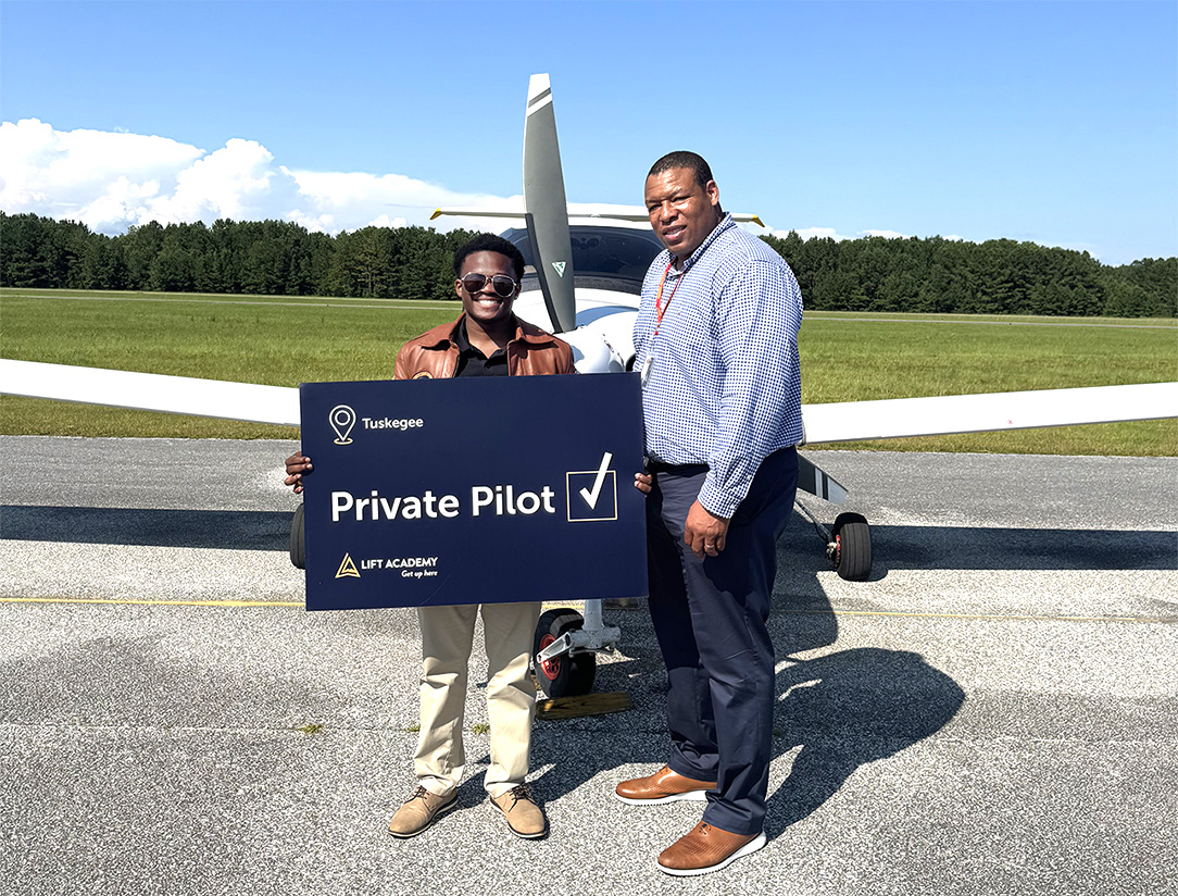 Picture of Isaiah Hand standing at airplane with program director Titus Sanders.