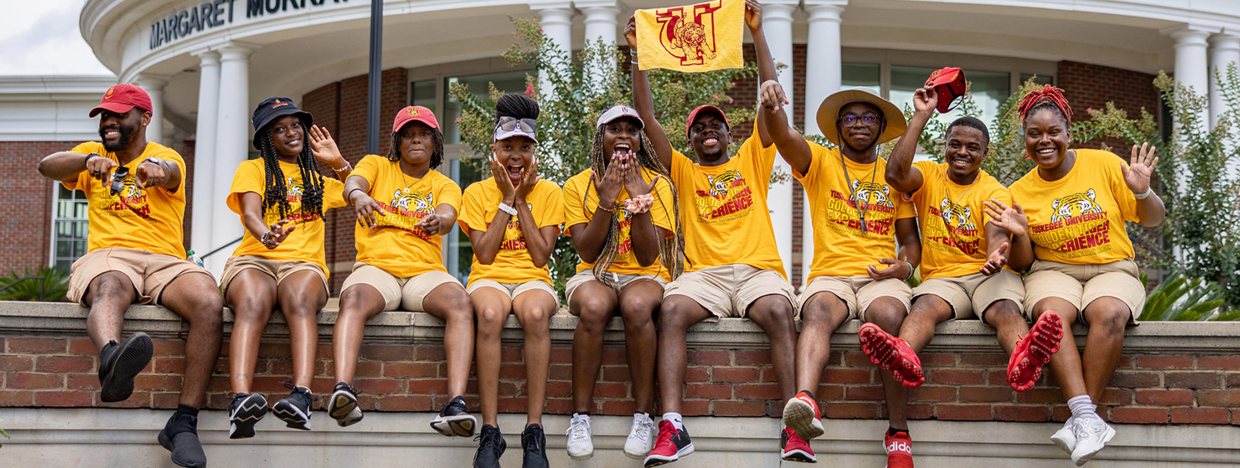 Students sitting at front entrance to campus